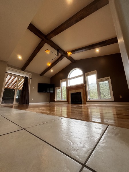 Vaulted great room with exposed wood beams, arched window and fireplace